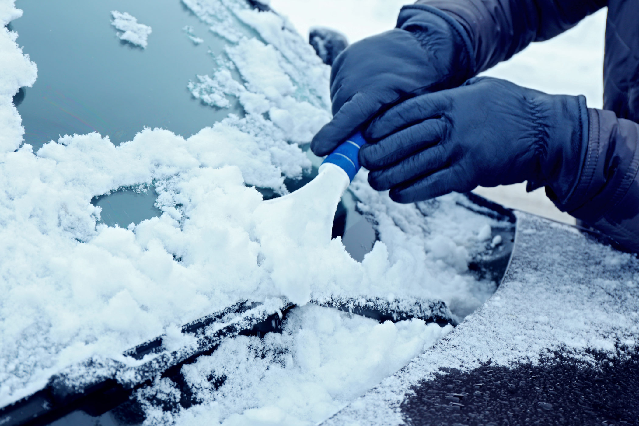 Removing snow from car windshield, closeup