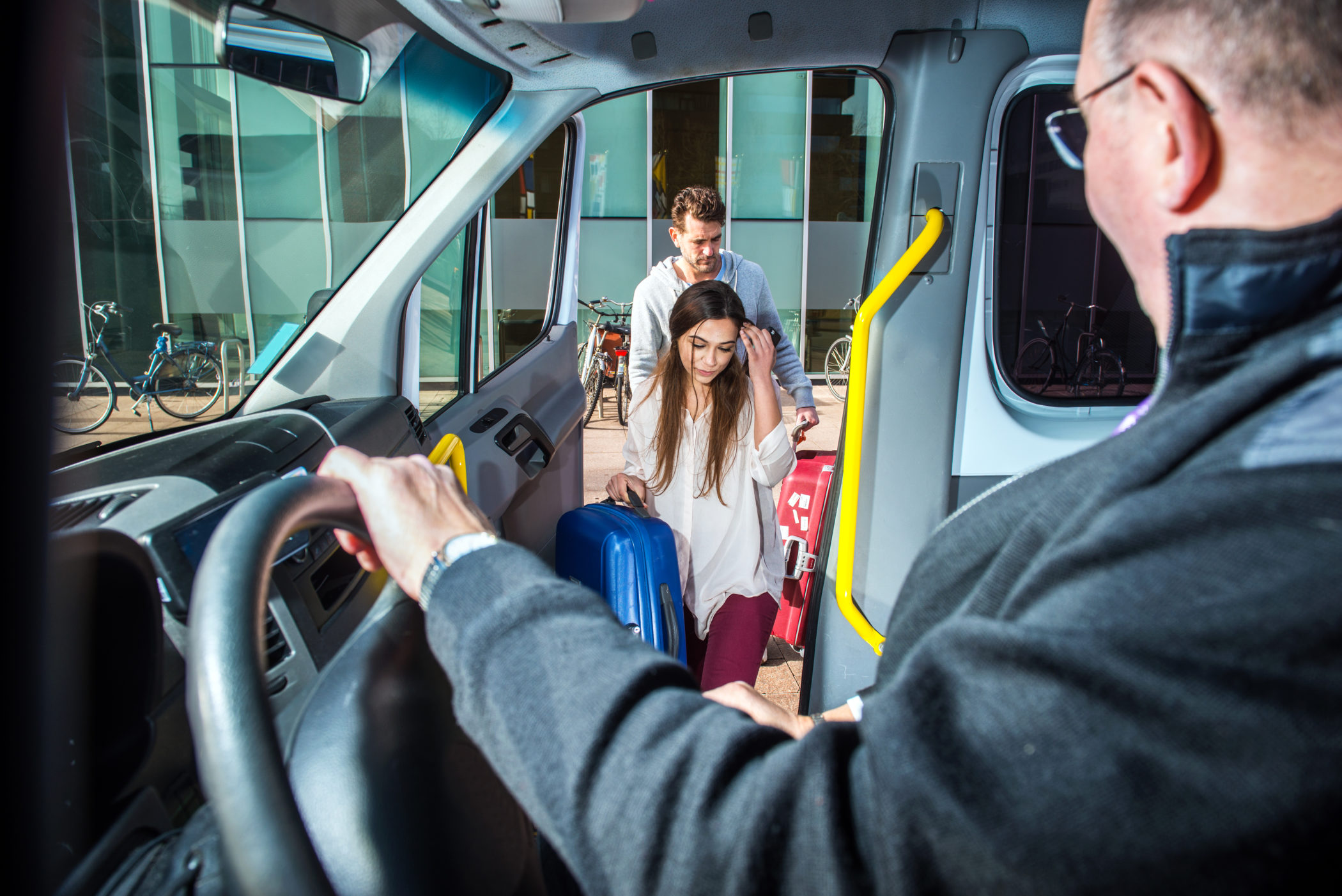 Minivan taxi picking up two passengers, carrying luggage to take them to the airport